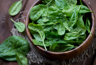 Wooden bowl with fresh spinach leaves, close-up, high angle view